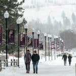 Students walk on a snowy sidewalk on their way to class at the University of Montana.